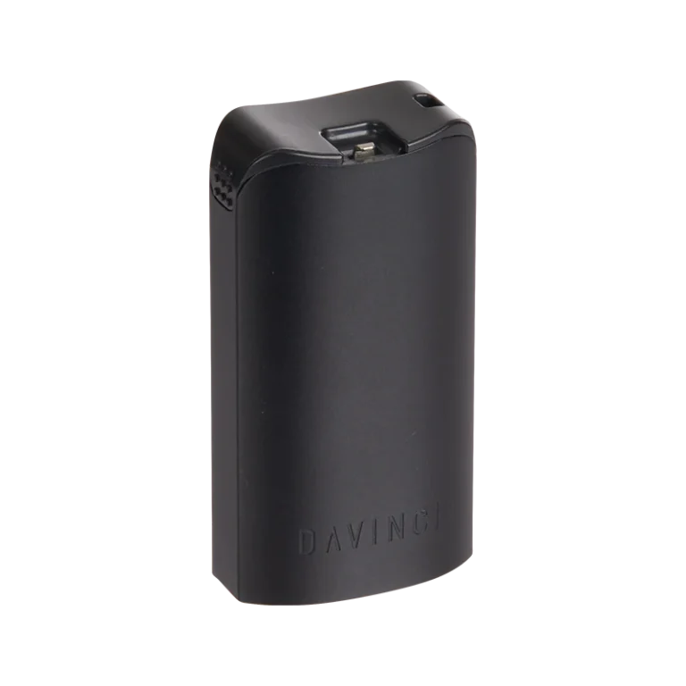 DaVinci MIQRO Dosage Holder in matte black, shown at a slight angle. A compact, rectangular accessory with rounded edges, featuring a hinged metal clasp on top, a small vent or button detail on the left side, and the 'DAVINCI' brand name embossed on the front face.
