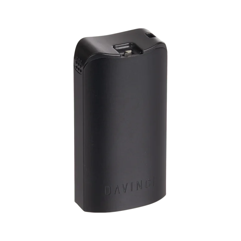 DaVinci MIQRO Dosage Holder in matte black, shown closed. A compact rectangular accessory with rounded edges, an integrated packing tool and pod extractor snapped into the lid, a small vent detail on the left side, and 'DAVINCI' embossed on the front face.