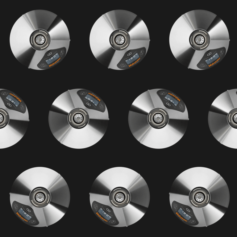 A repeating grid pattern of Storz & Bickel Volcano Hybrid vaporisers photographed from above against a black background, showing the polished stainless steel conical top, central mesh air outlet, and LED display reading 180°C with the 'Volcano Hybrid' logo in orange.