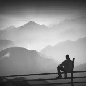 Person sitting outdoors overlooking misty mountain landscape in New Zealand