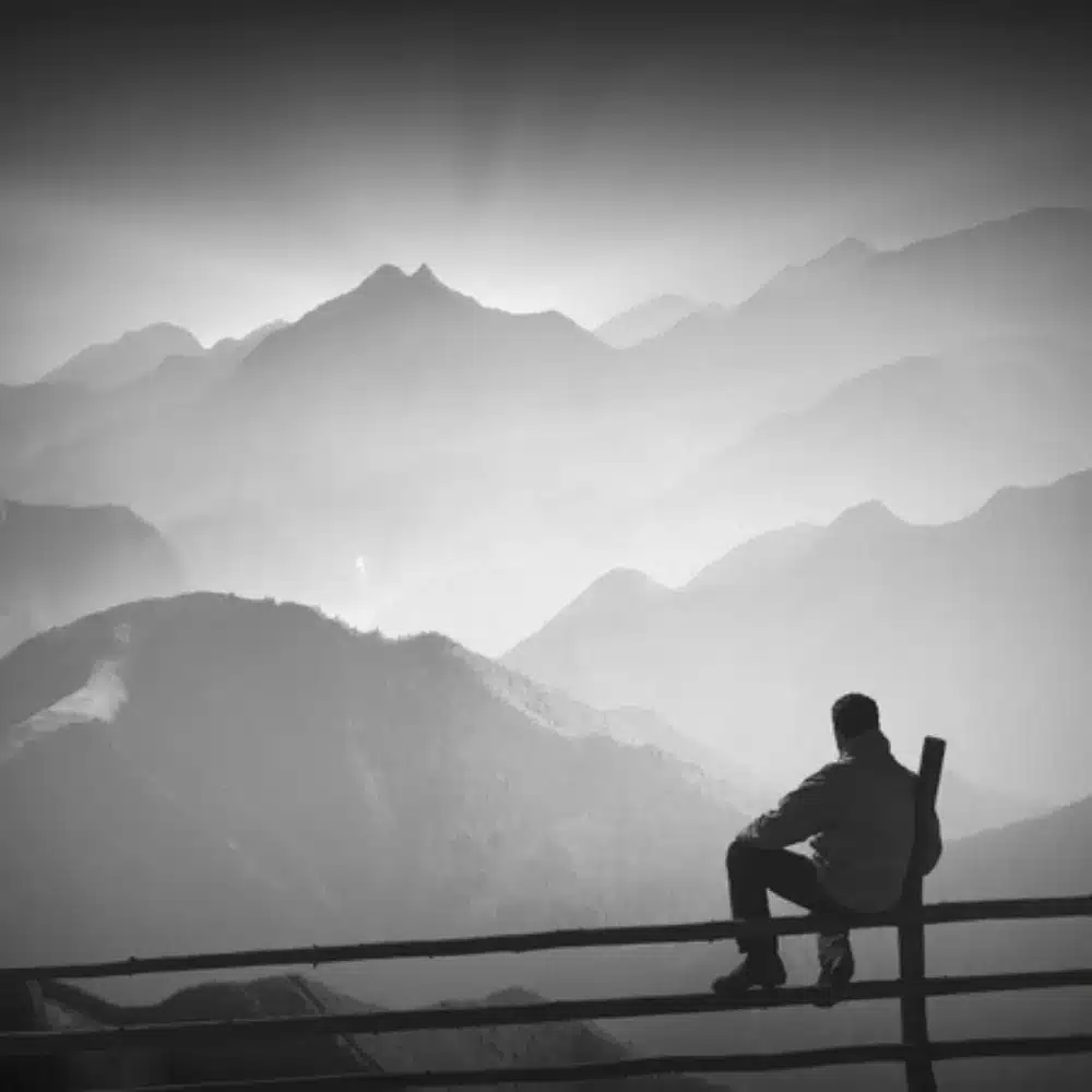 Person sitting outdoors overlooking misty mountain landscape in New Zealand